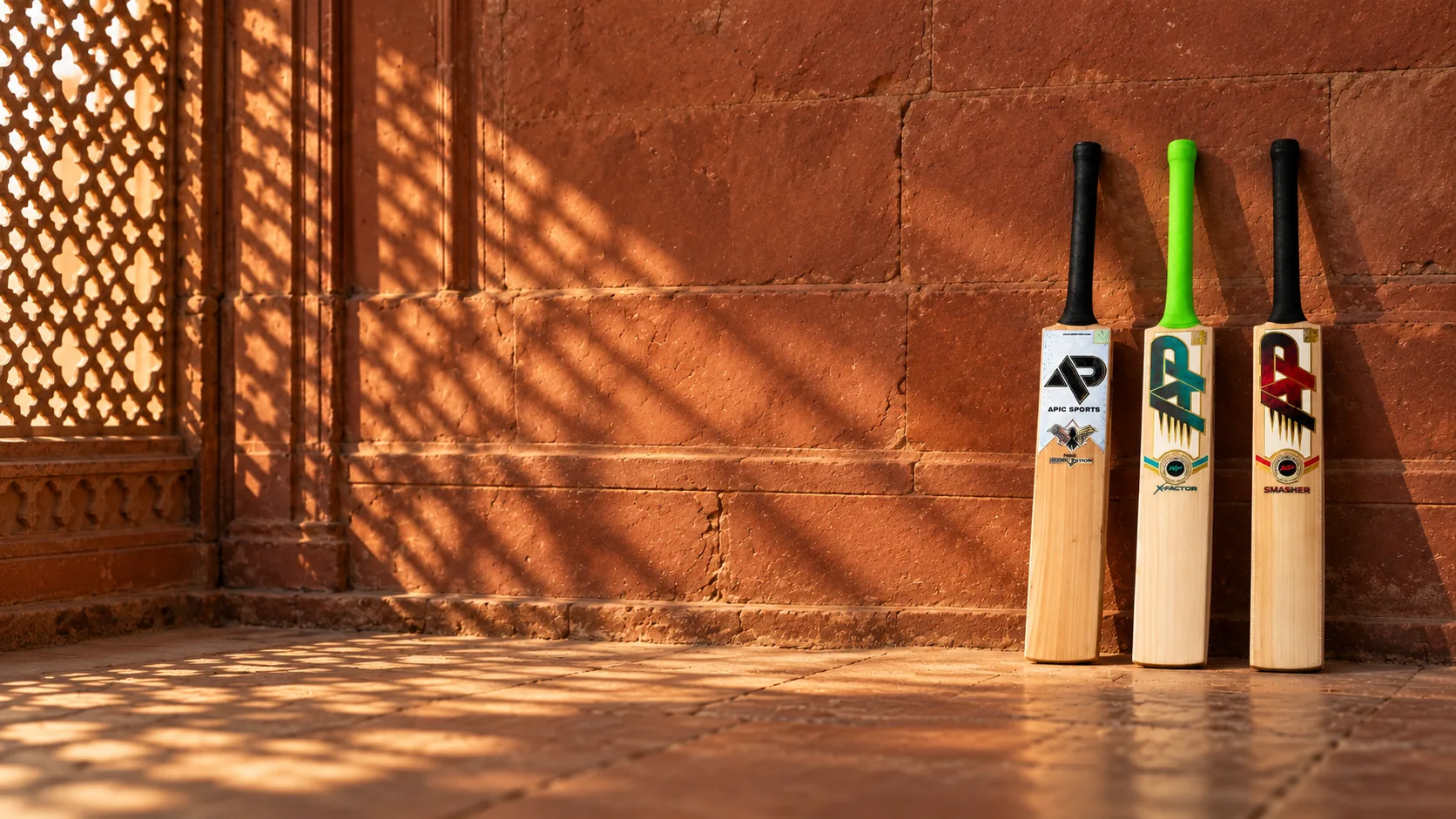 The Hawk, X-Factor and Smasher leaning on a red sandstone wall, in light through a carved jali screen