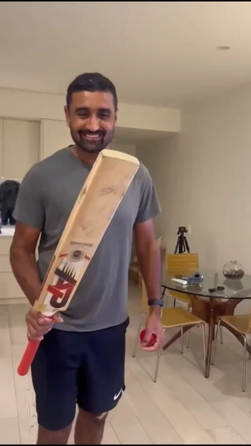 A smiling player holding a well-used APICS Smasher and a red ball